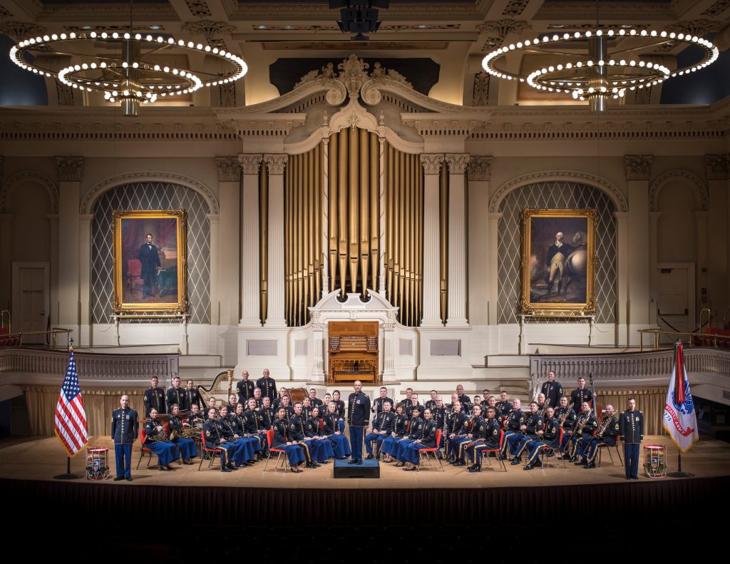 Iso joukko seisomassa koristeellisessa konserttisalissa.